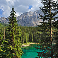The lake Lago di Carezza / Karersee surrounded bij mountain peaks and pine forest in the Dolomites, Italy